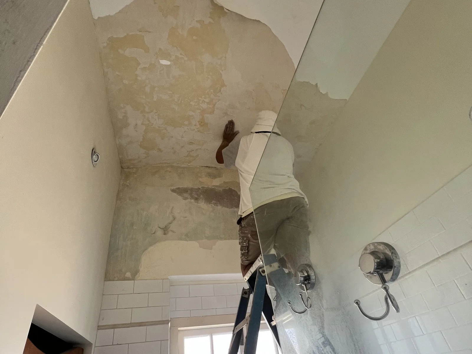 Painter stripping old paint from bathroom walls before repainting